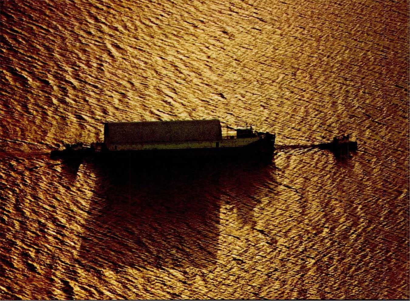 A photo of a rocket-laden barge being escorted by two tug boats