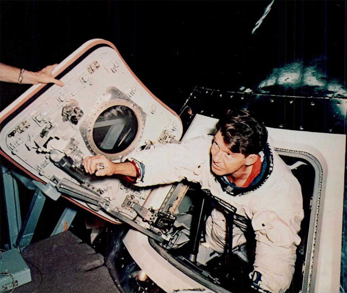 A photo of astronaut Wally Schirra inspecting the new hatch of the capsule