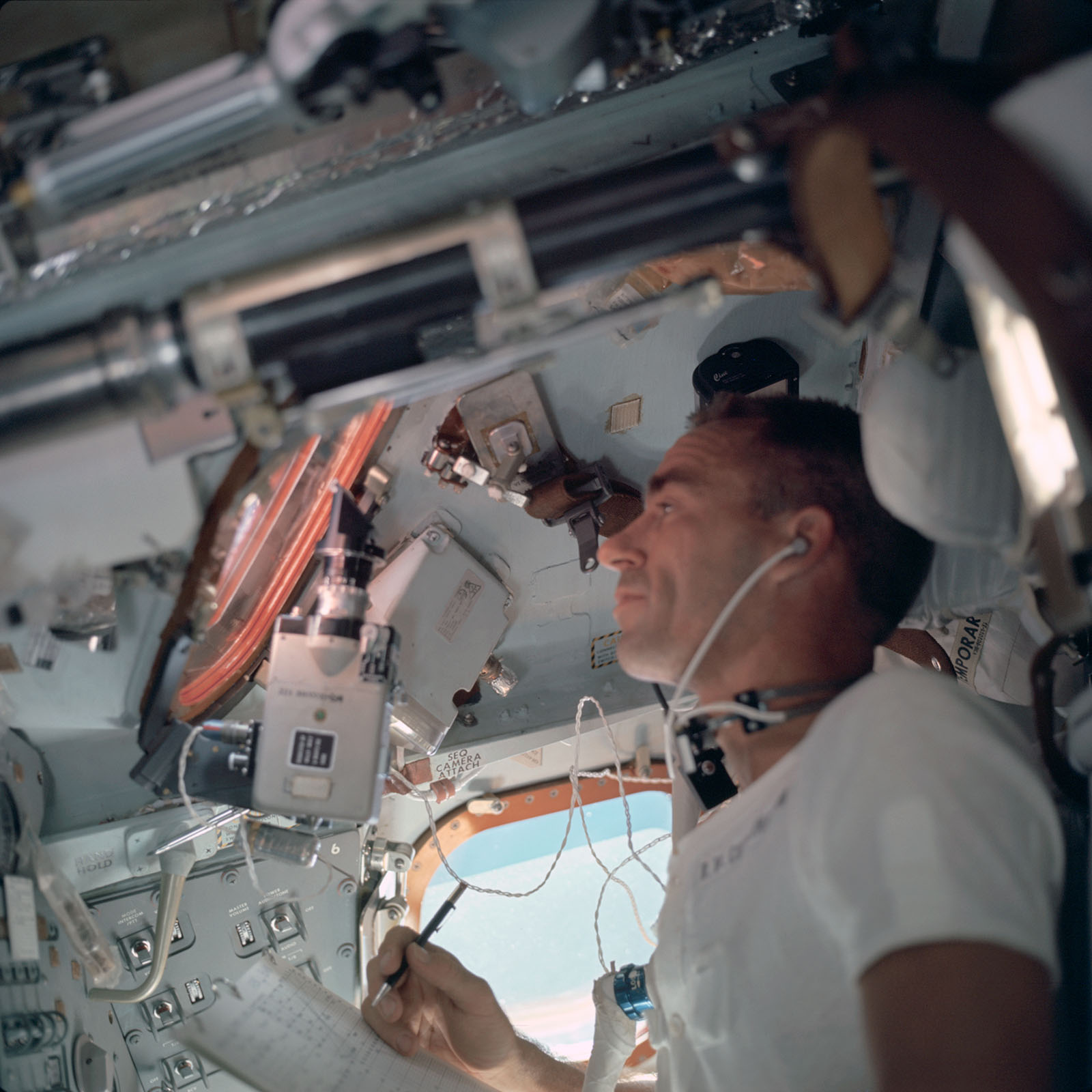 A photo of astronaut, Cunningham looking through a spacecraft window