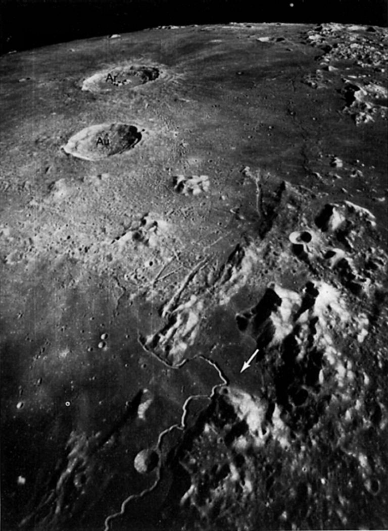 FIGURE 29. - The Apollo 15 landing site, marked by an arrow, is visible in this north- looking oblique photograph. This is one of the northernmost views photographed during the Apollo missions. The Caucasus Mountains are on the upper right horizon, with Mare Serenitatis off the image on their right and Mare Imbrium on their left.