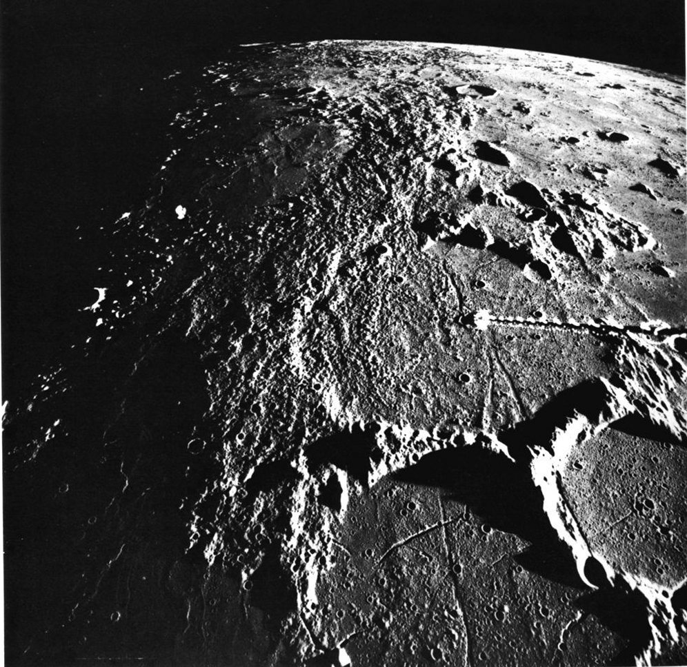 FIGURE 44. - A north looking oblique view of the region surrounding the Apollo 14 landing site (arrow), about 600 km south of the Imbrium basin, which is just beyond the horizon. 