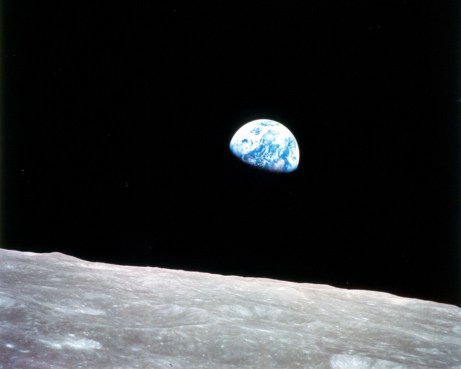 space photo of moon horizon in foreground and partialy visible cloud coverd earth in space